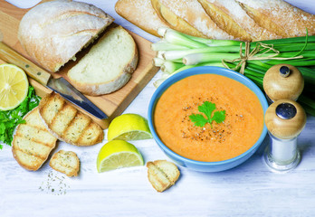Delicious  lentil soup in blue bowl placed with fresh ciabatta bread,green onion,lemon on white wooden background.Top view..