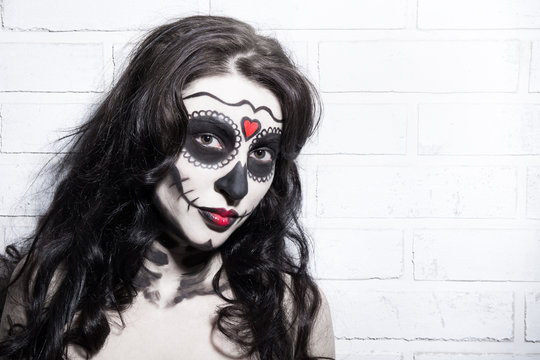 Halloween concept - beautiful woman with creative sugar skull ma