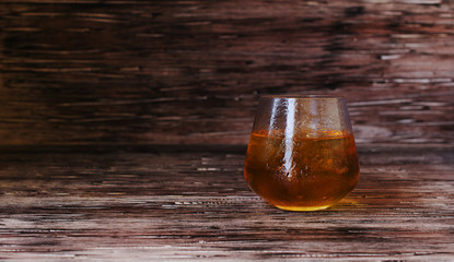 glass of whiskey with ice on rustic wooden table