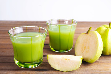 Close up of a healthy glass of fresh guava juice and fresh guava on a wooden table.