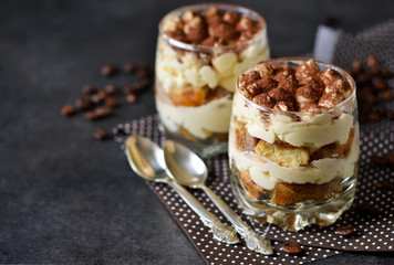 Classic tiramisu in a glass jar on black background