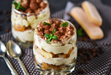 Classic tiramisu in a glass jar on black background