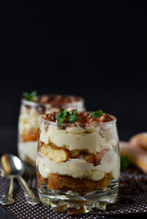 Classic tiramisu in a glass jar on black background