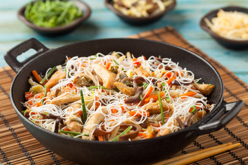 Rice noodles with chicken, mushrooms mun and vegetables in wook.