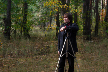 a guy with a tripod in the forest   