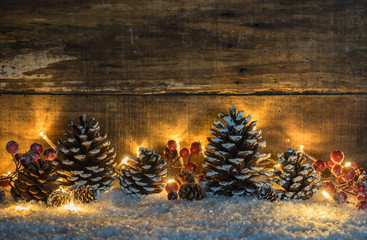 Weihnachtsstimmung Dekoration Rustikal, Zapfen und Beeren im Schnee mit Lichterkette