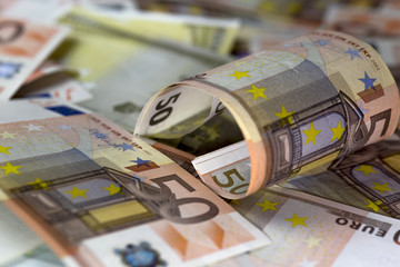 Half rolled fifty euro banknote on fifty euros banknotes background. Close up shot, Selective focus.