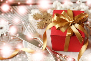 Christmas table setting with festive decor and gift. Snowy effect