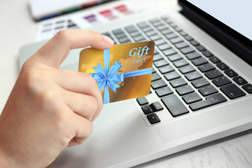 Woman with gift card and laptop, closeup. Shopping online. Holiday celebration concept.