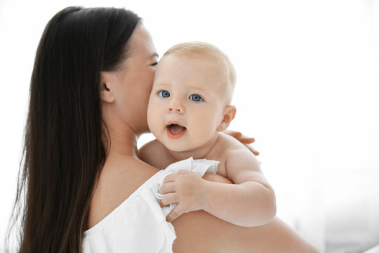 Mother holding little baby on light background