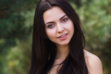 Naklejka premium Graceful charming brunette model posing in black dress in coniferous park