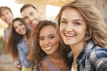 Happy friends taking selfie on street