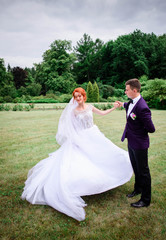 happy and young groom and bride standing together outdoors