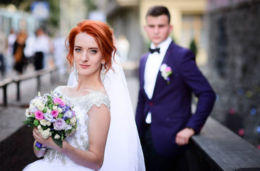 beautiful and young groom and bride standing together outdoors