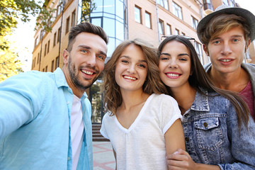 Happy friends taking selfie on street