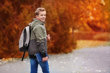 Cheerful teenager walking in autumn park