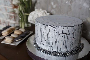 White cake decorated with crystals stands on the wooden bar