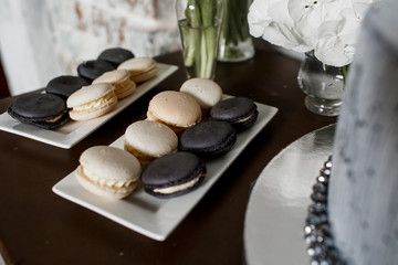 Black and white macaroons stand on square plates before white bo