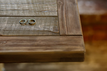 Wedding rings lie on the corner of wooden table