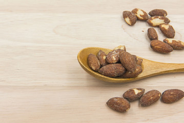 Almonds, salt in a wooden spoon. on wood background.