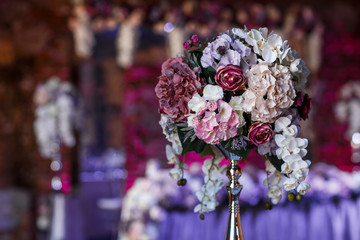 Bouquet made of pink, red and violet flowers stands on steel vas