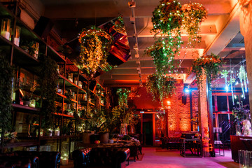 Naklejka premium Shining lamps with greenery hang from the wall before wooden she