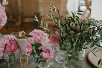 Decorative greenery and pink peonies stand on dinner table