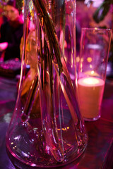 High vase with candle stands behind vase with flowers