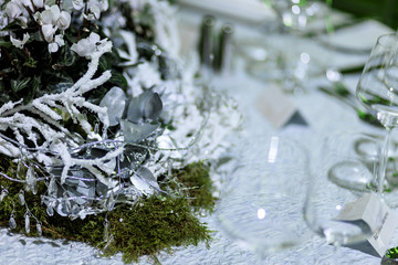 Empty glasses stand on dinner table decorated with artificial sn