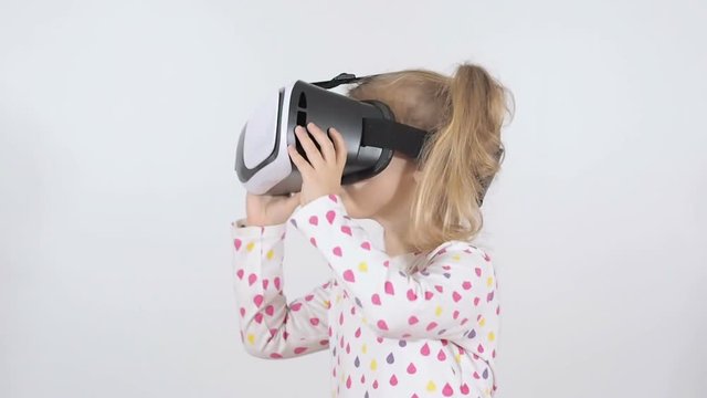 Virtual reality game. little girl with surprise and pleasure uses head-mounted VR display on a white background