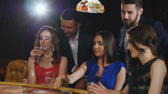 A group of young and beautiful people drinking champagne and playing blackjack