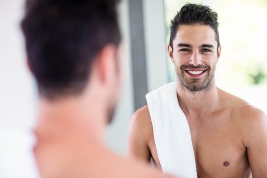 Handsome shirtless man looking in the mirror