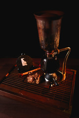 Fototapeta na wymiar Puer tea in the siphon with extruded pancake Shu Puer and Buddha statue on black background. Chinese tea ceremony