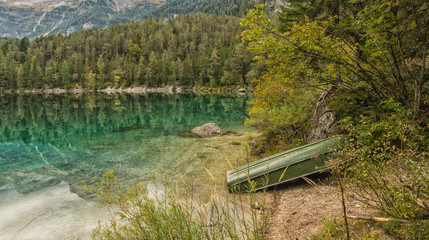 Obraz premium crystal clear mountain lake at sunset with light and sun filtering.Lake Tovel in Autumn. Italy