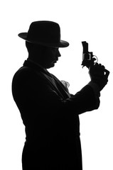 Fototapeta na wymiar Silhouette of private detective with a gun in right hand. Agent stay side to camera and looks like mafioso Al Capone. Criminal scene. Studio shot
