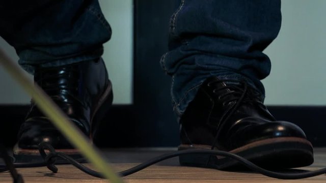 Man stands and tap his feet to rhythm - detail of legs