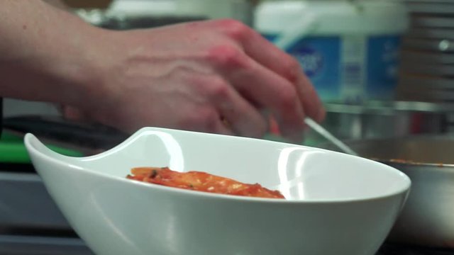 Man serves a sauce to bowl - close up bowl and stewpan