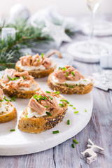 Slices of baguette with fresh tuna, cream cheese and chopped onion chives on marble board. Christmas themed dinner table.