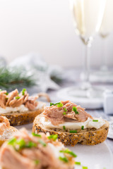 Slices of baguette with fresh tuna, cream cheese and chopped onion chives on marble board. Christmas themed dinner table.