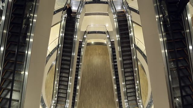 The girl down the escalator, she is shopping in the mall
