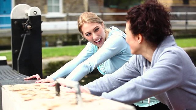 Two girls doing stretching exercises outdoors in London

