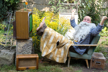 Cheerful TV fans sitting at garden with television