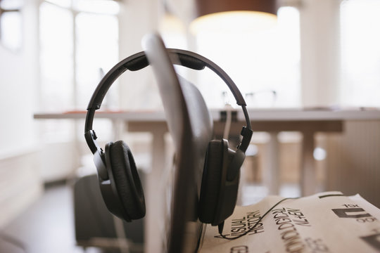 A pair of black headphones hanging on the back of chair in a light interior.