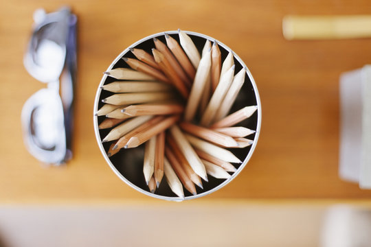 A can of lead pencils and sunglasses on a desk.