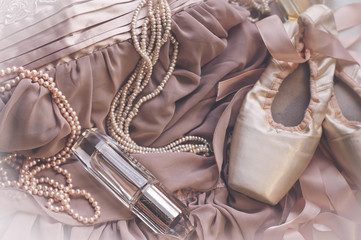 Woman's fashion outfit. Close up of a silk ceremony shoes, pearl necklace, satin dress and perfume
