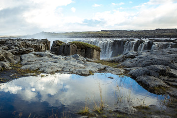Сlouds reflection in a puddle. Sellfoss and Dettifoss waterfall