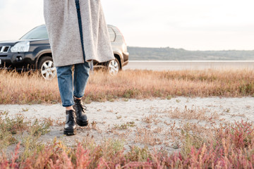 Casual woman walking outside with car on background