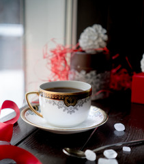 ancient antique cup tea on the Christmas table with presents  the background of a winter window