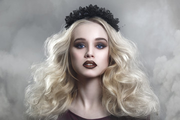 Beauty portrait of a beautiful young blonde woman with gothic make-up and decorative wreath in a...