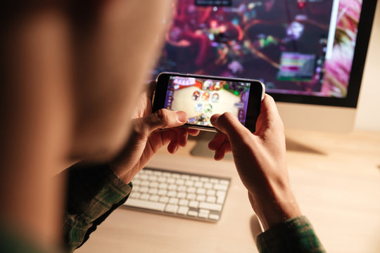 Closeup of man playing videogame on smartphone in evening